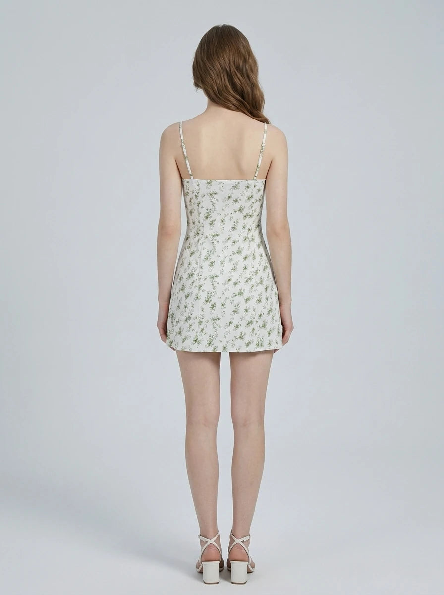 Woman wearing a white floral print mini dress with spaghetti straps and a sweetheart neckline.