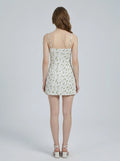 Rear view of a woman in a white floral print mini dress.