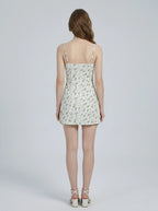 Rear view of a woman in a white floral print mini dress.