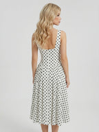 Back view of a woman in a white polka dot fit and flare dress