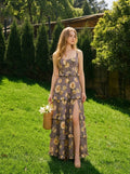 Woman in a grey floral print maxi dress with ruffles and a high slit, standing in a grassy area with trees.