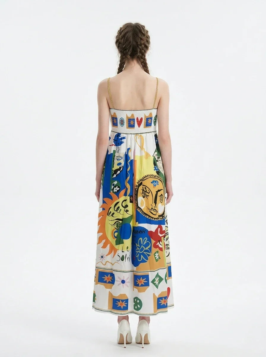 Woman wearing a white midi dress with a colorful abstract graphic print and gold chain spaghetti straps.