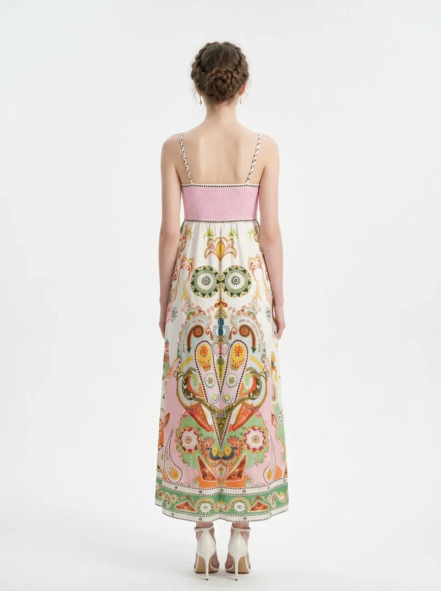 Woman wearing a long, printed sundress with spaghetti straps and a square neckline, standing against a white background.