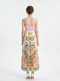 Rear view of a woman in a printed sundress with a smocked back panel and spaghetti straps.