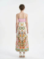 Rear view of a woman in a printed sundress with a smocked back panel and spaghetti straps.