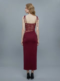 Back view of a woman in a burgundy dress with lace detailing and tie shoulder straps.