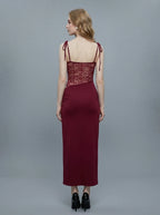 Back view of a woman in a burgundy dress with lace detailing and tie shoulder straps.