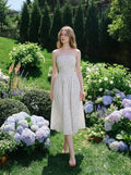 Woman walking in a garden wearing a floral print midi dress.