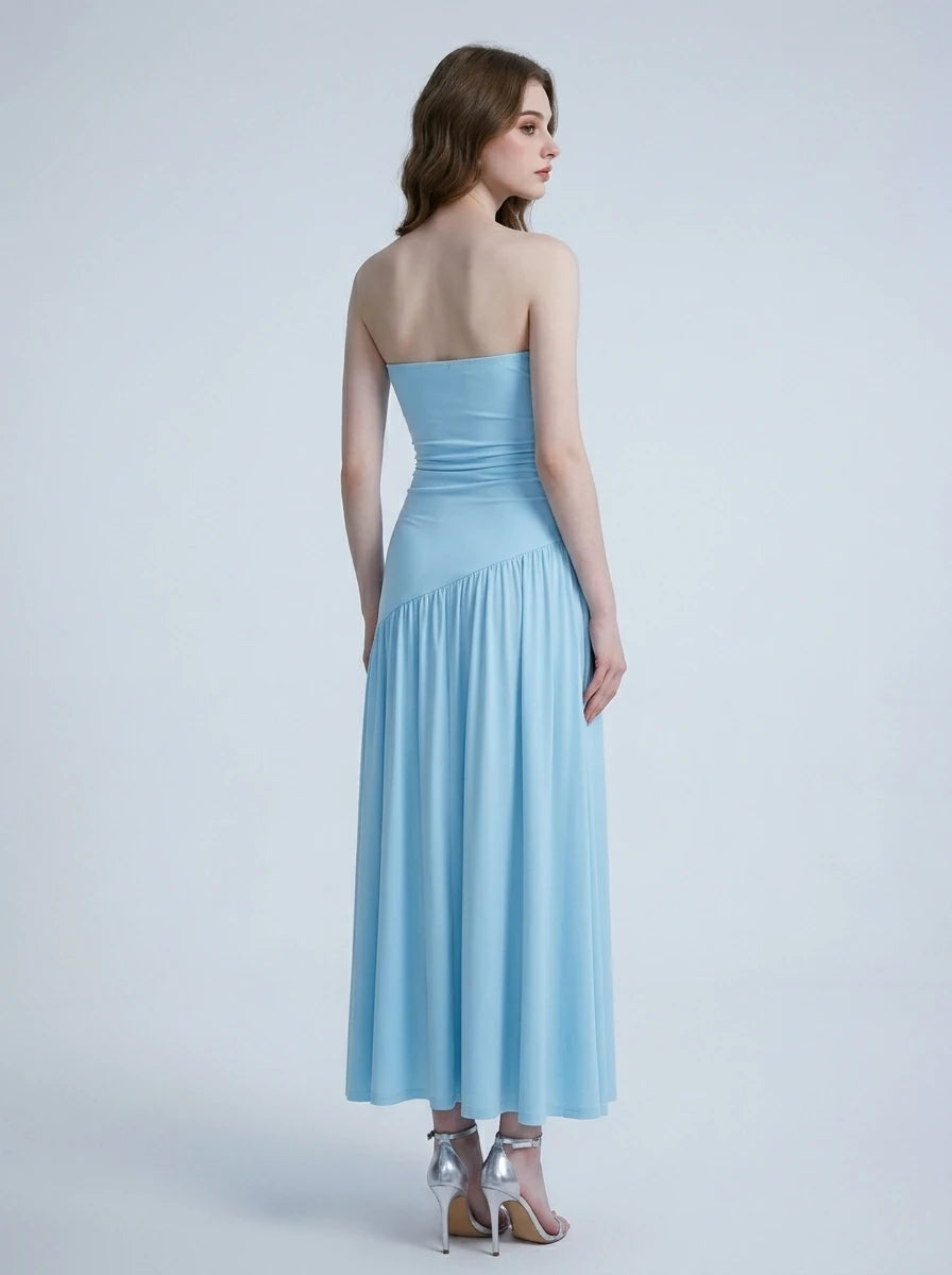 Back view of a woman in a sky blue strapless ruched jersey knit A-line evening dress with an asymmetrical hemline and side slit