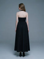 back view of a woman in a black midi halter dress with a smocked back