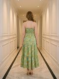 Back view of a woman in a green floral print strapless maxi dress with a smocked back.