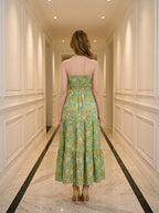 Back view of a woman in a green floral print strapless maxi dress with a smocked back.