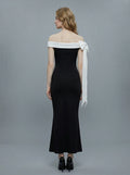 Rear view of a woman in a black off-the-shoulder mermaid dress with a white draped accent on the shoulder.