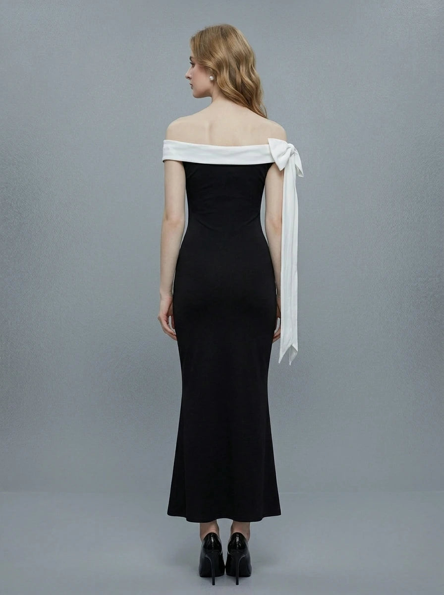 Rear view of a woman in a black off-the-shoulder mermaid dress with a white draped accent on the shoulder.