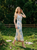 Woman wearing a floral print midi dress walking in a grassy outdoor setting.