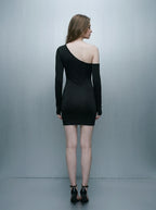 Back view of a woman in a black asymmetrical mini dress with one long sleeve.