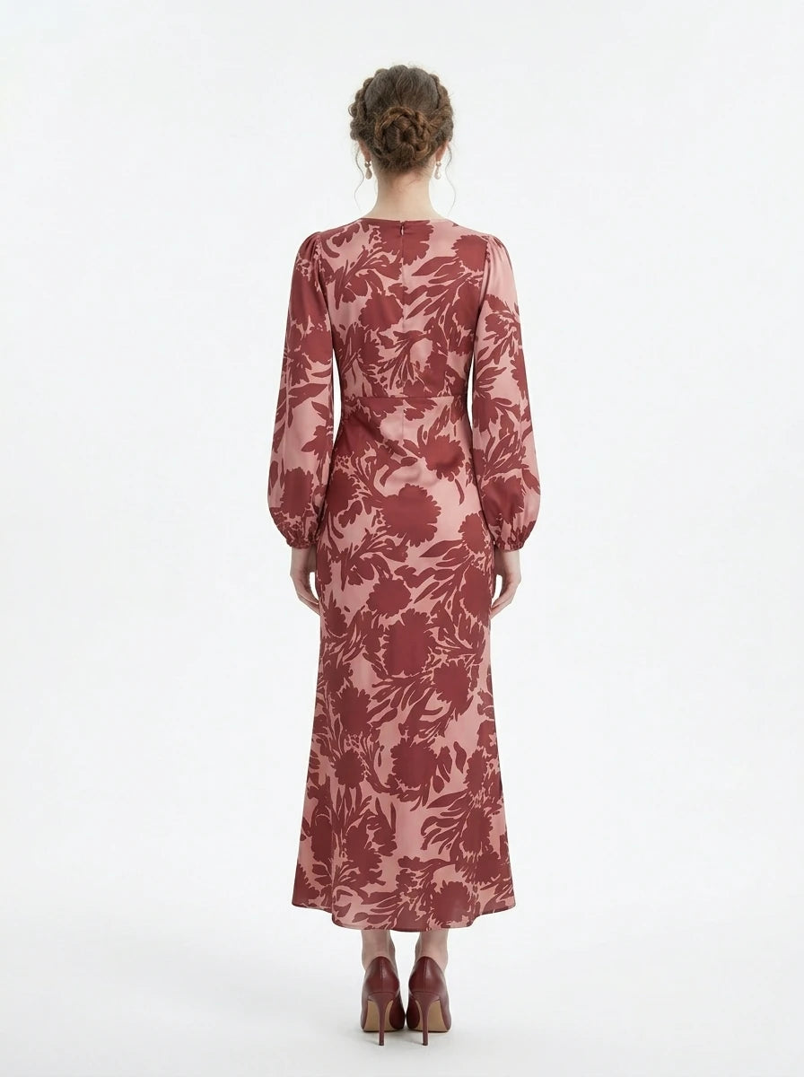 Back view of a woman in a long, floral print, V-neck dress with long balloon sleeves.