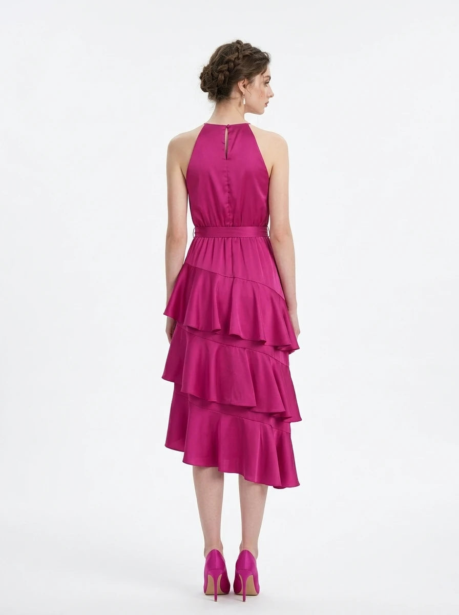 Woman wearing a fuchsia satin halter neck tiered midi dress with a self-tie belt