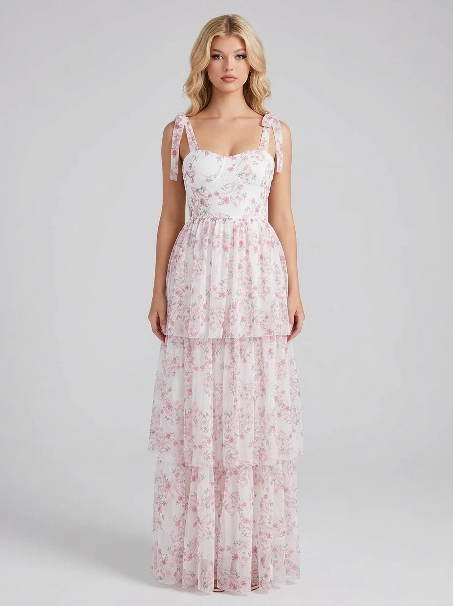 Woman wearing a white and pink floral print maxi dress with tiered skirt and tie shoulder straps