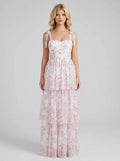 Woman wearing a white and pink floral print maxi dress with tiered skirt and tie shoulder straps
