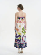 Woman wearing a white midi dress with a colorful graphic print and spaghetti straps from the back