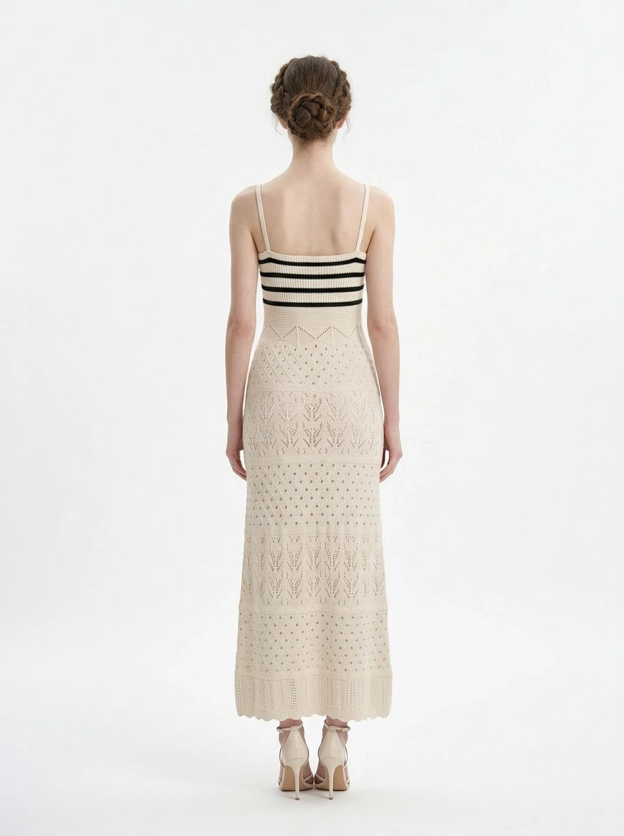Woman wearing a cream knit maxi dress with black striped bodice and spaghetti straps, front view