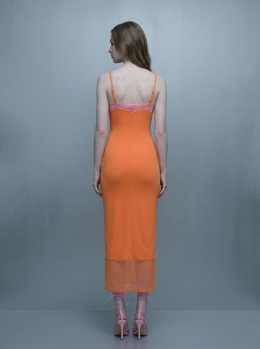 Back view of a woman in an orange slip dress with pink lace trim and sheer hem.