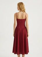 Back view of a woman in a deep red linen blend midi dress with spaghetti straps and a fitted bodice