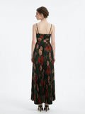 Woman in a dark green floral print maxi dress with spaghetti straps and a pleated skirt, back view