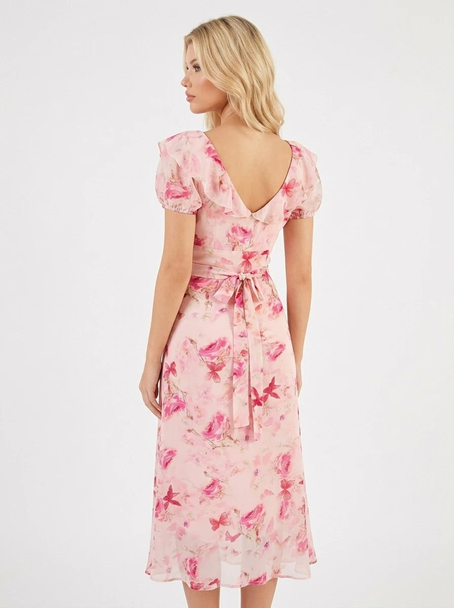Woman wearing a pink floral print midi dress with a v-neck and tie-front detail.