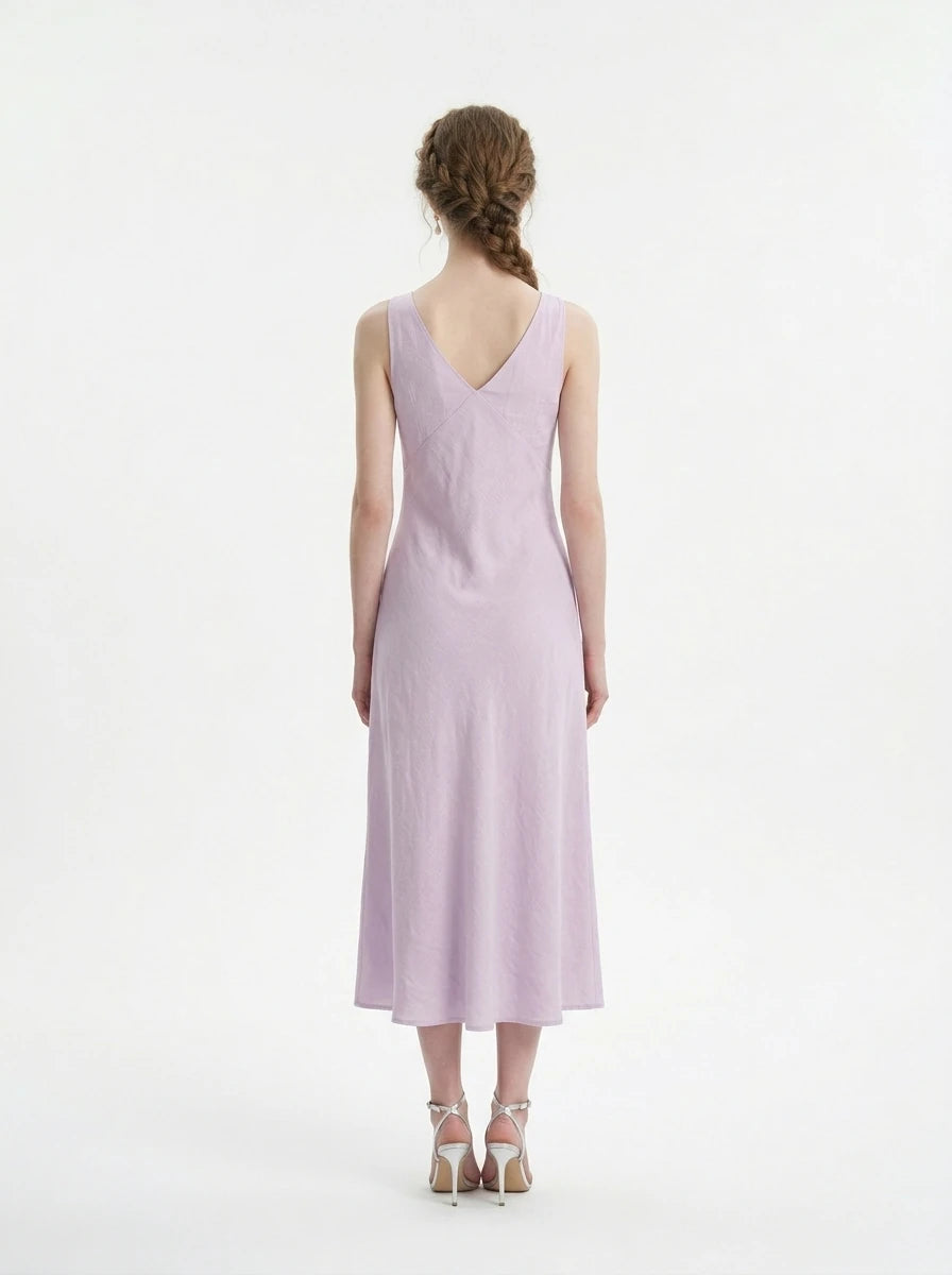 Back view of a woman in a lilac midi dress with a V-neckline and sleeveless design.