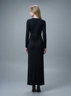 Rear view of a woman in a black long-sleeved V-neck gown with a ruched detail on the back.