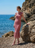 Model standing on rocks by the sea in Dusty Rose Lace Midi Dress