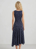 Back view of a woman in a navy blue polka dot midi dress