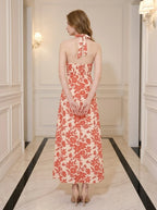Back view of a woman in a coral floral print halter neck midi dress