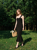Woman in a black one-shoulder mermaid dress with a sweetheart neckline and ruched bodice, walking in a park.