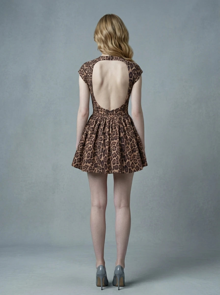 Woman in leopard print fit and flare dress with crew neck and cap sleeves standing against a grey background.