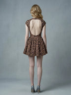 Back view of woman in leopard print fit and flare dress with open back, crew neck, and cap sleeves.