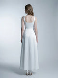 Back view of a woman in a white satin floor-length dress with a square neckline and tank straps, standing against a white background.