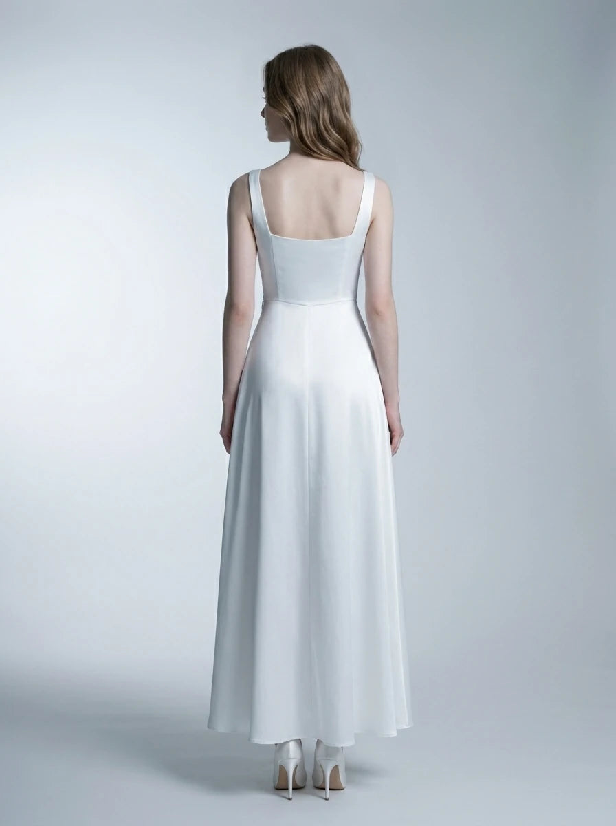 Back view of a woman in a white satin floor-length dress with a square neckline and tank straps, standing against a white background.
