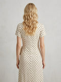 Back view of a woman in a cream polka dot midi wrap dress
