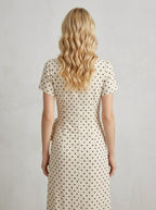 Back view of a woman in a cream polka dot midi wrap dress