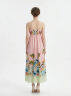 Back view of a woman in a pink midi dress with spaghetti straps and a tropical print.