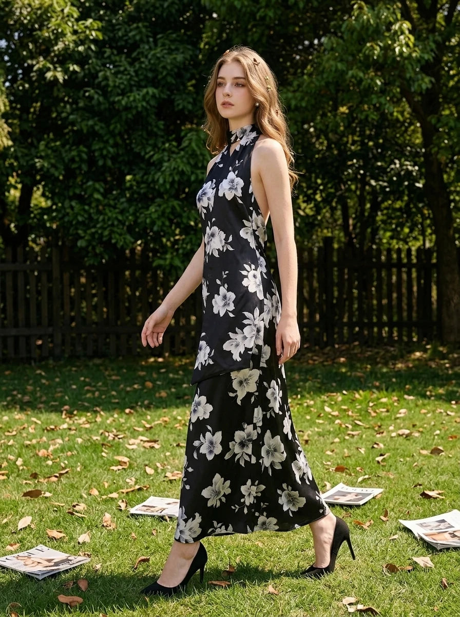Woman walking in a grassy area wearing a black floral print halter maxi dress