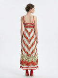 Back view of a woman in a white maxi dress with a red floral print and red trim.