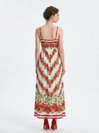Back view of a woman in a white maxi dress with a red floral print and red trim.