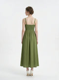 Woman wearing a green linen blend midi dress with a smocked bodice and spaghetti straps, back view.