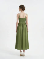 Woman wearing a green linen blend midi dress with a smocked bodice and spaghetti straps, back view.