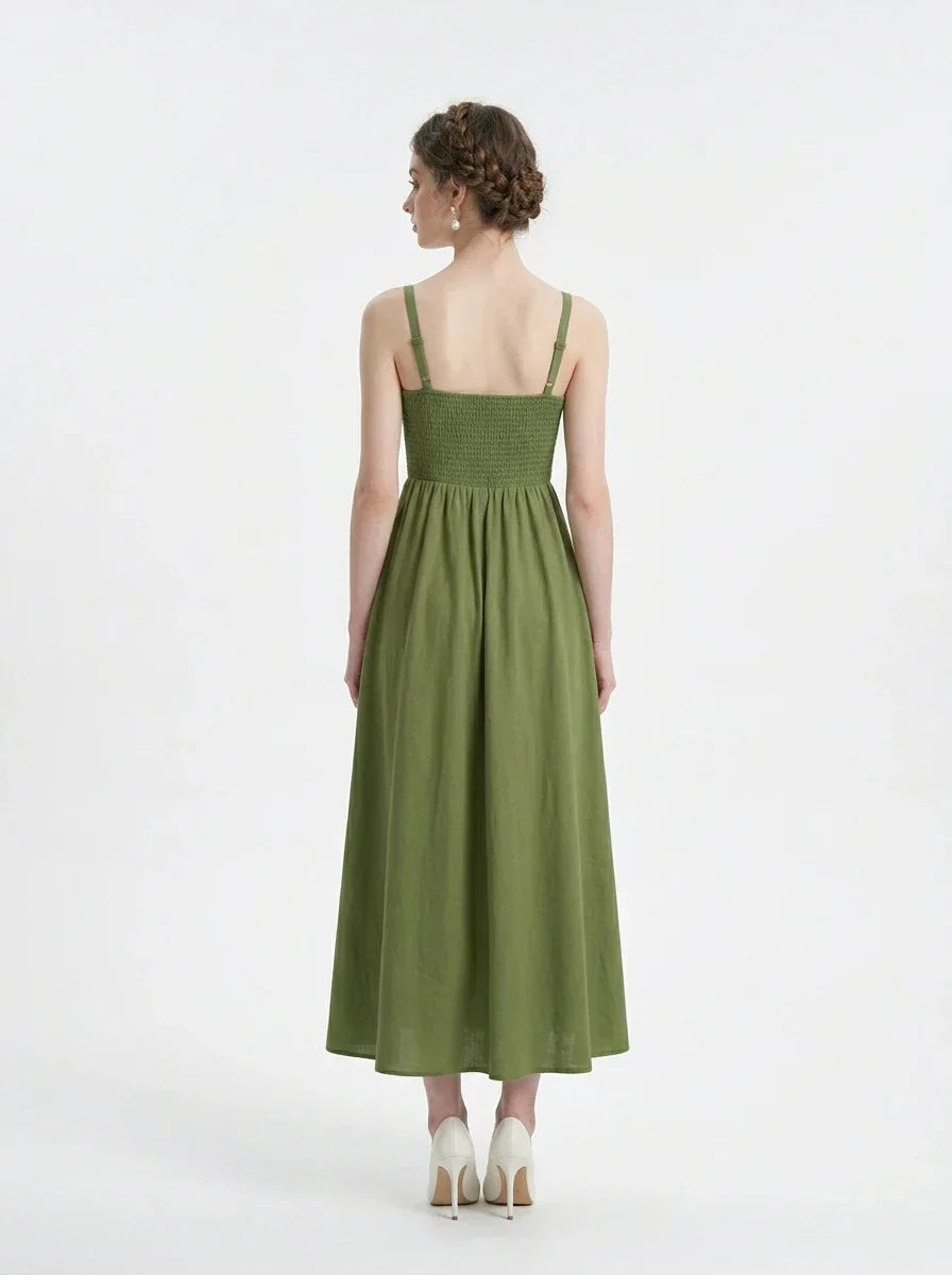 Woman wearing a green linen blend midi dress with a smocked bodice and spaghetti straps, back view.