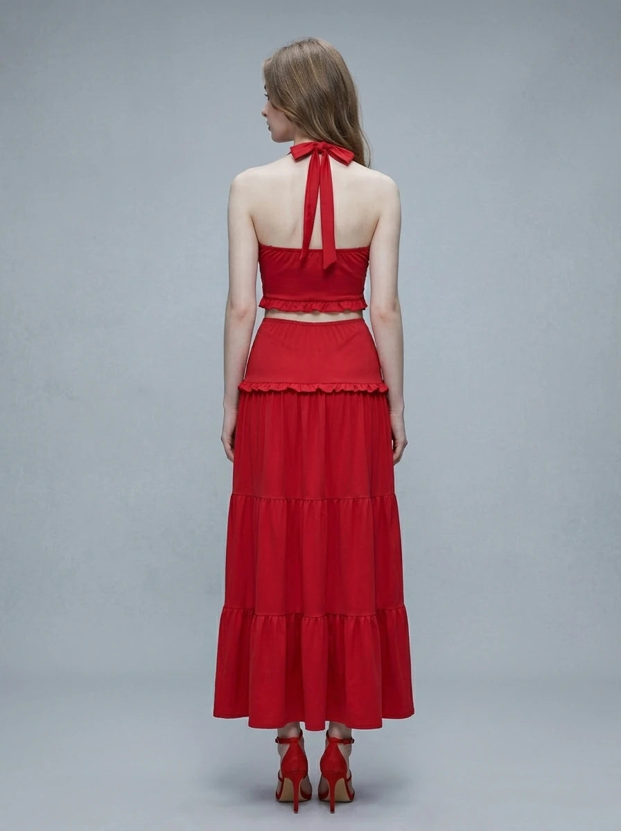Woman wearing a red halter neck crop top and a tiered maxi skirt.